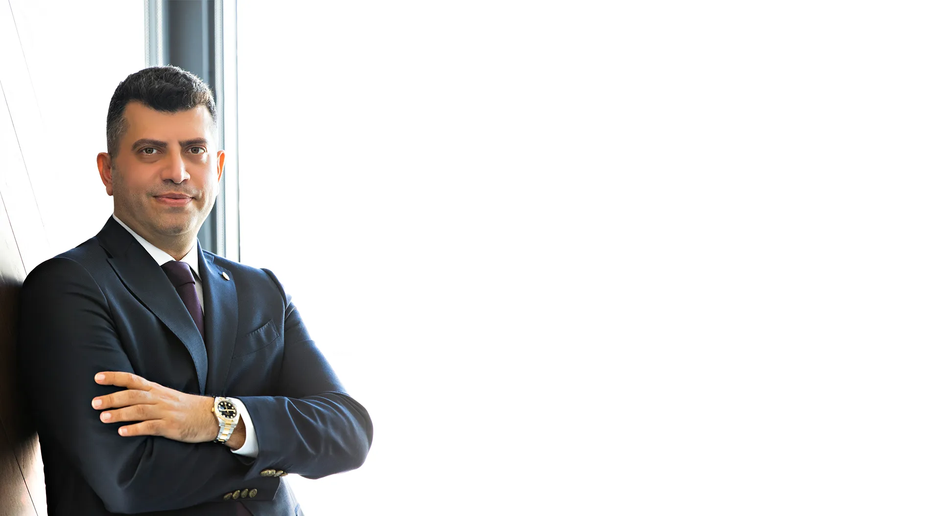Op. Dr. Cenk Teker, ENT surgeon, standing by a window in a navy suit